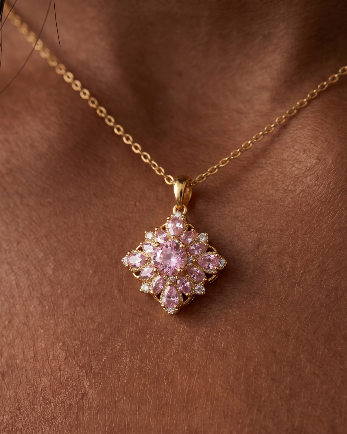 Gold-tone necklace with a pink flower pendant, close-up of the pink petals against the chest.
