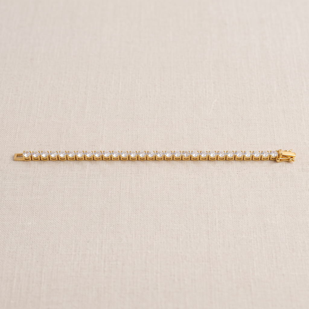 Gold-tone tennis bracelet laid flat, showing a row of round clear stones and an open clasp.