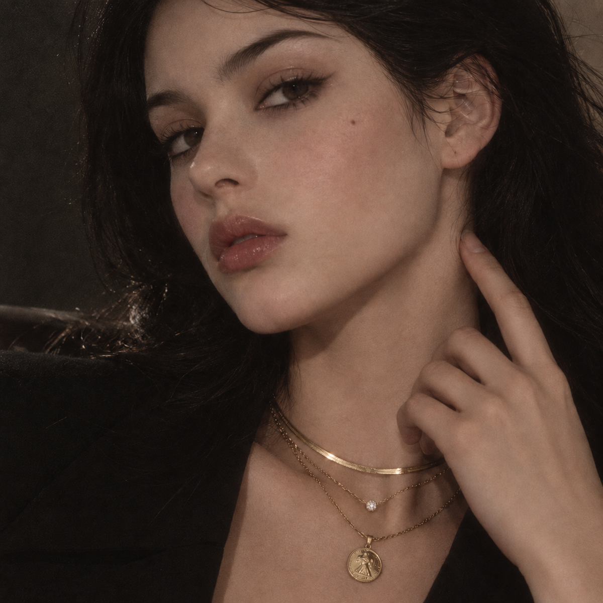 Portrait of a model wearing layered necklaces and a coin pendant.