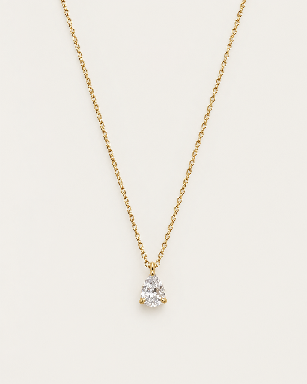 Gold-tone chain necklace with a single pear-shaped clear stone pendant.