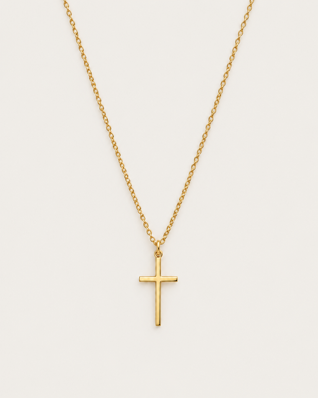 Gold-tone cross pendant hanging from a fine chain against a light background.