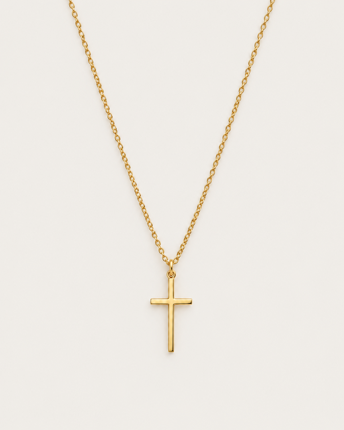 Gold-tone cross pendant hanging from a fine chain against a light background.